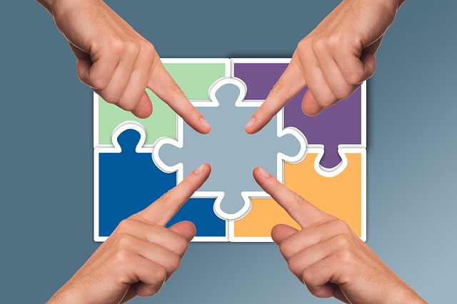 IPM104 Course Image: Abstract puzzle containing five coloured pieces overlayed with four hands pointing to the centre of the image