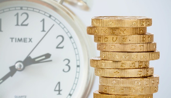 IENT103 Course Image: Image compilation showing stack of gold coins in the foreground with faded clock face in the background